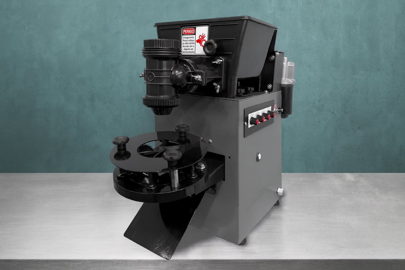 Máquina de corte de chaves sobre bancada de inox, com fundo largo em parede de concreto azul esverdeado.