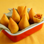 Coxinhas massa de mandioca douradas, crocantes, recheio suculento.