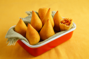 Coxinhas massa de mandioca douradas, crocantes, recheio suculento.