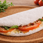 Aqui está a versão mais larga e ultra realista da tapioca que você pediu. **Descrição curta:** Tapioca brasileira dobrada, recheada com tomate fresco, folhas de manjericão e queijo derretido.